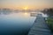 Wooden jetty on a calm and misty lake during sunset