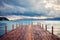 Wooden jetty on the calm sea, mountains and cloudy sky at dawn