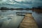 Wooden jetty on a lake and dark clouds on sky