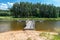 Wooden jetty near the beach, next to the lake. Spruce forest on the other side of the water.