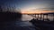 Wooden jetty on sea lake with a reflection in the water at sunset