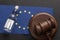 Wooden judge gavel and bottle of alcohol, EU flag background. Alcohol lawsuit in European Union concept