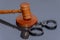 Wooden judge`s gavel and police handcuffs on a dark background. Concept: claim and compensation for damages, court session, announ