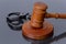 Wooden judge`s gavel and police handcuffs on a dark background. Concept: claim and compensation for damages, court session, announ