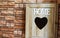 Wooden key box holding on the wall with heart in the middle. Letters Home in white and square tiles at the entrances of the home.