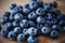 On a wooden kitchen board lie ripe sweet forest blueberries. Rich harvest