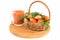 On a wooden kitchen board there is a glass with a rich, healthy tasty carrot juice and a wicker basket with carrots.