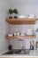 Wooden kitchen shelves with tableware on white ceramic tile wall in Scandinavian style