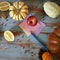 On the wooden kitchen table pumpkins, nuts, apples, paper and pencil to write down the recipe