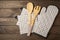 Wooden kitchen utensils, cutting board, potholder and glove on the table.