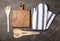 Wooden kitchen utensils, cutting board, potholder and glove on the table.