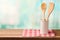 Wooden kitchen utensils on table with tablecloth over blue bokeh background with copy space for product montage