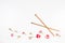 Wooden knitting needles and fresh roses on white background