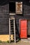 Wooden ladder on a cottage wall with red door