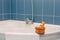 Wooden ladle with a brush, washcloth and other shower accessories on the rim of a corner bathtub near a terry towel