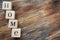 Wooden letter cubes on dark brown wooden table. Word `HOME`. Background.