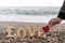 Wooden letters forming the word love and a hand holding a red heart on the seashore. concept of st. valentine`s day