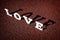 Wooden letters forming word LOVE written on sandy background