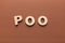 Wooden letters spelling Poo on brown background