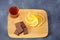 Wooden light board with a glass of cognac, chocolate wedges and lemon slices on a gray background