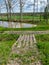 A wooden log bridge over a small ditch, wooden texture, bright green grass