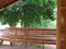 Wooden Long Bench at the Front Terrace with a Big Tree in Background