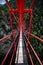 Wooden long footbridge above the deep gorge with a river beach at the bottom, between the rocks. Wild mountains in Swiss Alps