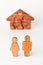 Wooden male and female figures in front of house on white background