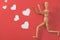 Wooden man figure running to catch red heart