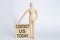 Wooden man shows with a hand text CONTACT US TODAY concept on the wooden block