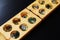 Wooden mangala game, mangala game board and glass marbles, on black background