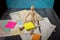 Wooden manikin figure sitting on folded scattered roadmaps holding a blank square yellow posted note
