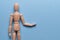 Wooden mannequin abstractly holds an object on a blue background