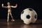 Wooden mannequin as a goalkeeper trying to catch the football. Black background, Selective focus. Football moment theme