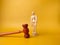 Wooden mannequin and gavel on a yellow background