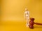 Wooden mannequin and gavel on a yellow background