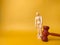 Wooden mannequin and gavel on a yellow background with copy space