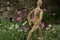 Wooden mannequin in the midst of spring flowers. Mediterranean garden with daisy with white and pink flowers and rotating model