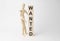 Wooden mannequin near tower of cubes with word wanted on table against light background