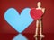 Wooden mannequin with red heart, Blurred heart shape in the background reflection. Saint Valentine theme