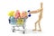 Wooden mannequin shopping easter eggs in shopping cart on white