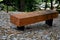 wooden massive park bench shape block with metal legs on granite natural cobblestone irregular brown gray pavement on pedestrian