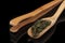 A wooden measuring spoon with green tea on a black background, a Chinese tea party