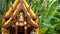 Wooden miniature guardian spirit house. Small buddhist temple shrine, colorful flower garlands. San phra phum erected to