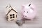 Wooden miniature house and pink piggy bank with Russian ruble co