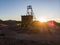 Wooden mining structure head frame on claim in the Nevada desert backlit sun flare