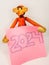 A wooden monkey toy with a sticky note with 2024.