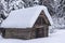 Wooden mountain shed, against the backdrop of snowy forest.