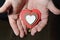 A wooden multicolored heart in the man`s hands on the palms.