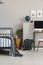 Wooden nightstand with spruce in glass vase and clock in grey kid`s bedroom interior with copy space on the empty grey wall